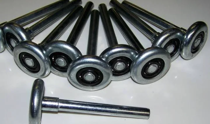Steel garage door rollers with stems and sealed bearings laid out on a white surface